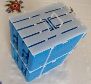 A cartridge containing five blue ice packs is placed on top of a second identical one.